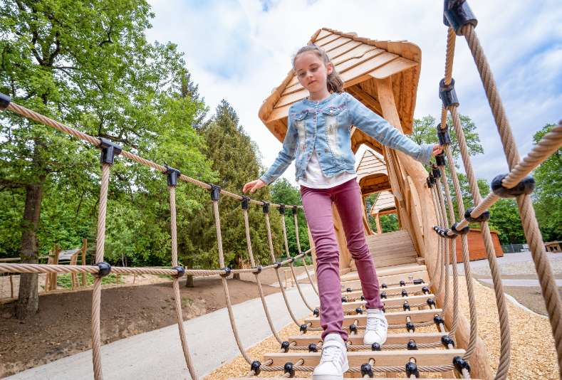 Les enfants exercent leur coordination de manière ludique sur le terrain de jeux de la Forêt d'Aventure Alsace.