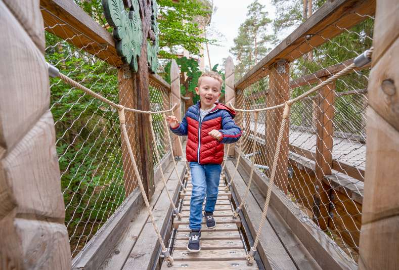 Ein Kind hat viel Spaß bei der Benutzung einer Abenteuerstation auf dem Chemin des Cimes Alsace.