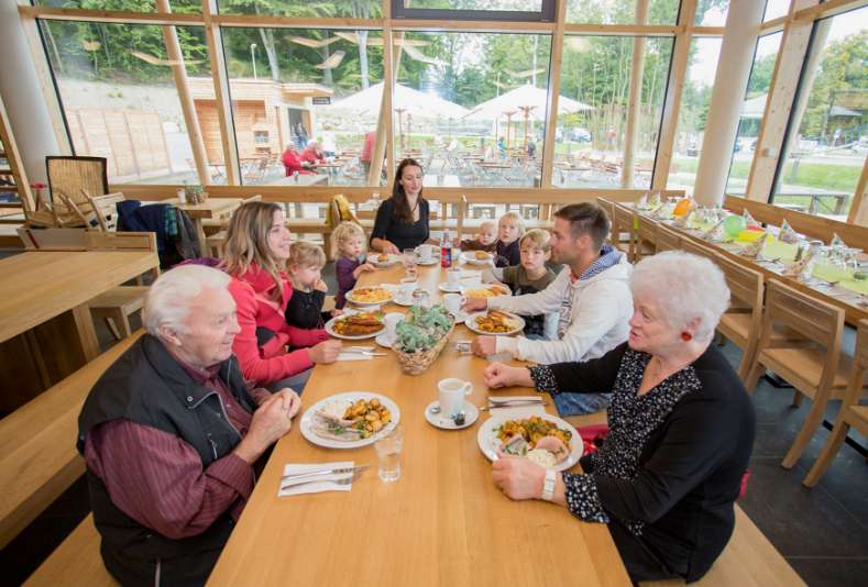 Eine Familie besucht den Baumwipfelpfad und stärkt sich anschließend bei reichhaltigem Mittagessen im Restaurant.