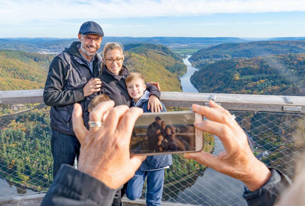 A family has their photo taken in front of the beautiful panorama of the observation tower.
