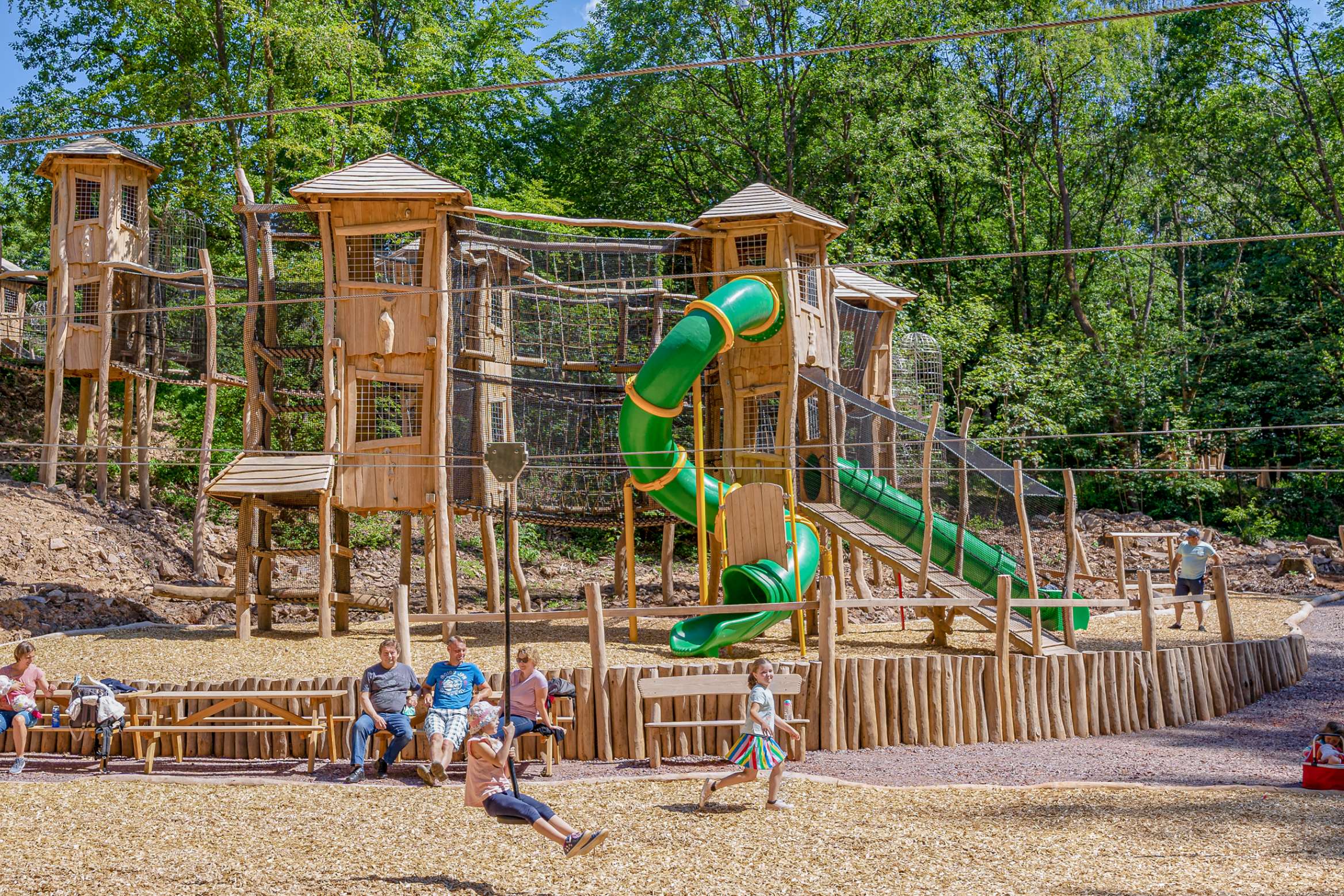 Children and families play on the equipment in the Adventure Forest Saarschleife.