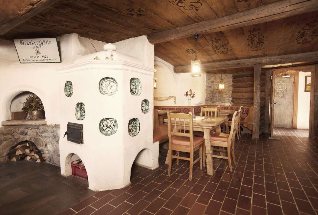 The guest room of the Grünbergalm with its wood-burning stove and rustic furnishings invites you to linger a while