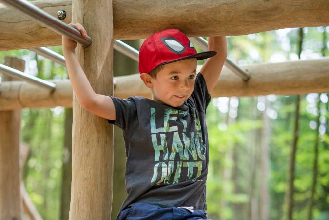 Junge baumelt an der Kletterleiter im Abenteuerwald Sommerberg hin und her