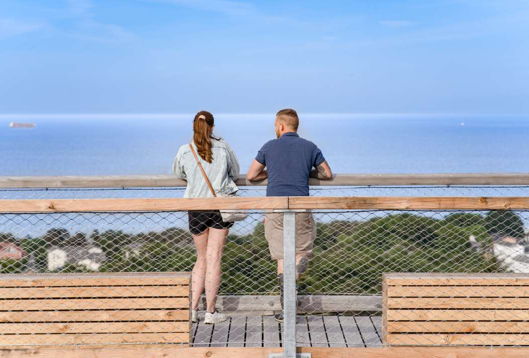 Para podziwiająca widok na morze z wieży widokowej Uznamskiej Ścieżki w koronach drzew.